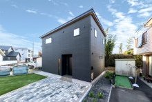 塗り壁調の黒い外壁とベージュの木目がソリッドな重厚感を与える