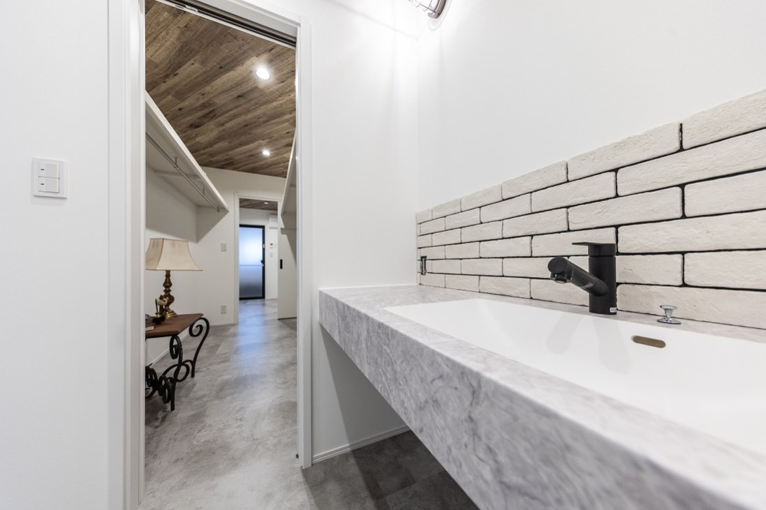 黒目地の白いブリックタイルが趣と白い空間をシャープに彩る洗面