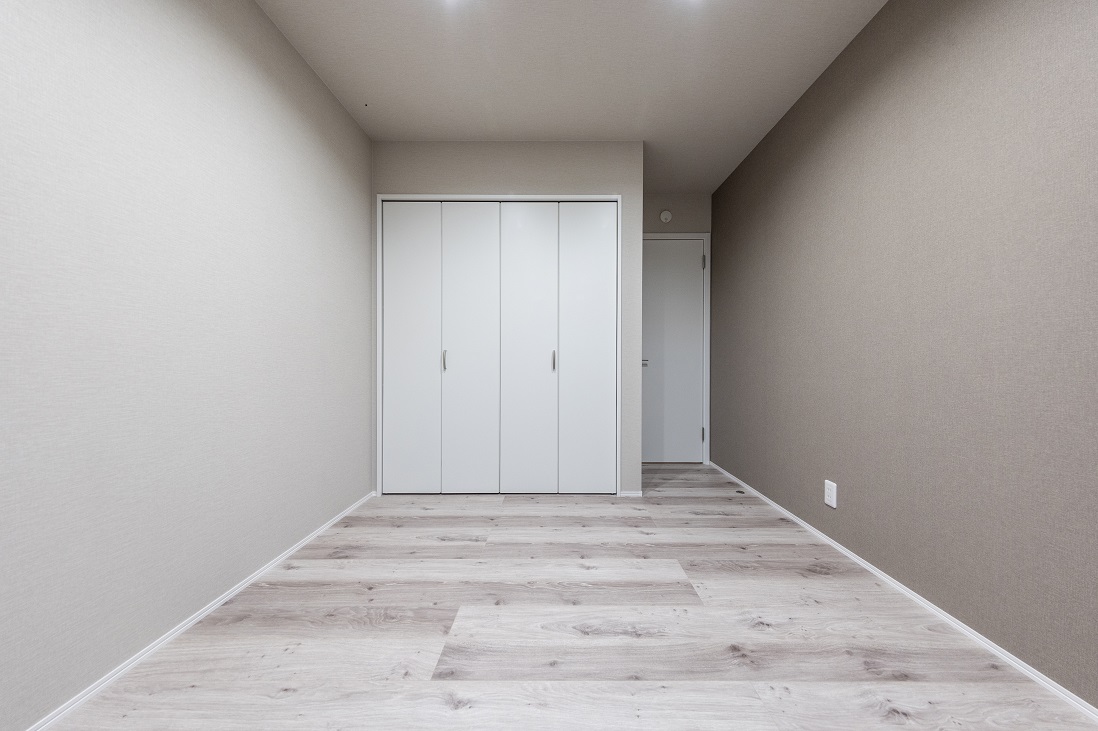 床・壁・扉をグレイッシュなトーンでまとめた落ち着ける寝室