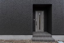チャコールブラックの外壁にグレイッシュなドアがシックなエントランス