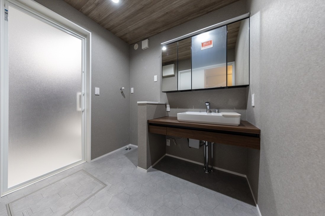 洗面室は、モルタル調をベースとしながらも木目が暖かみを与える