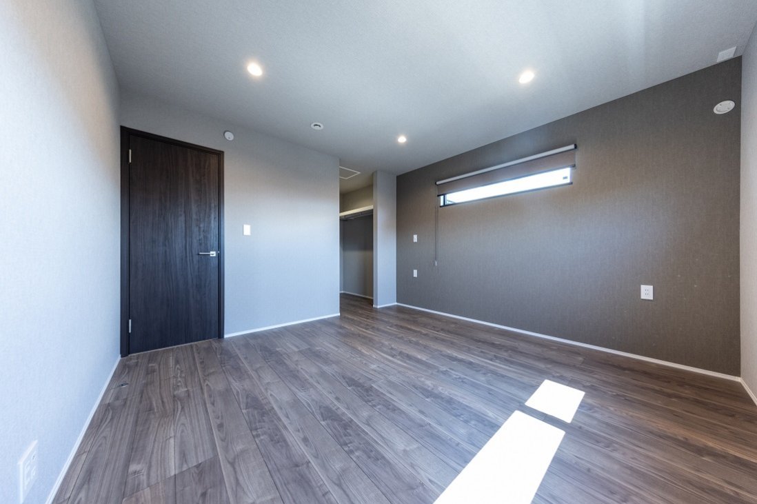 床と壁の印象を他の居室とは違うダークカラーで演出した主寝室