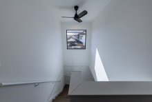 大きな窓とシーリングファンの存在がシンプルを際立たせる吹抜け階段