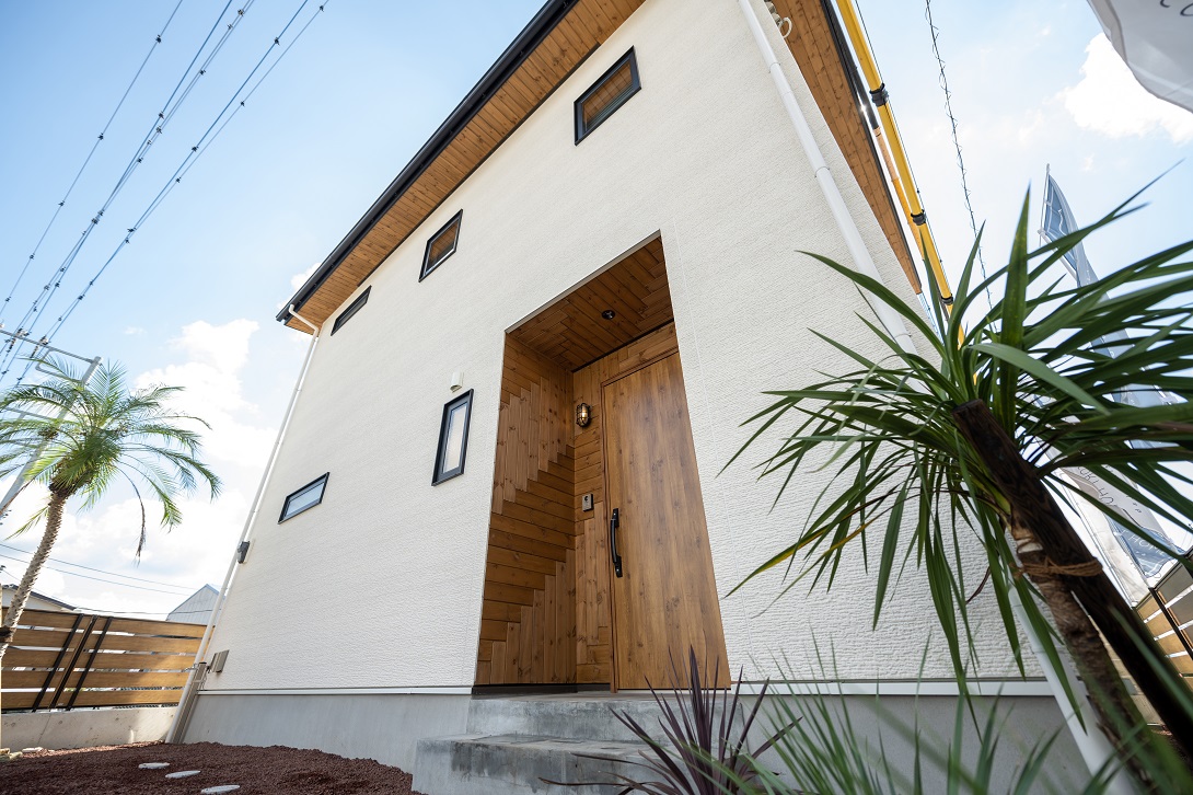 塗り壁調の白壁にウッドであしらった玄関がやさしく出迎えてくれる